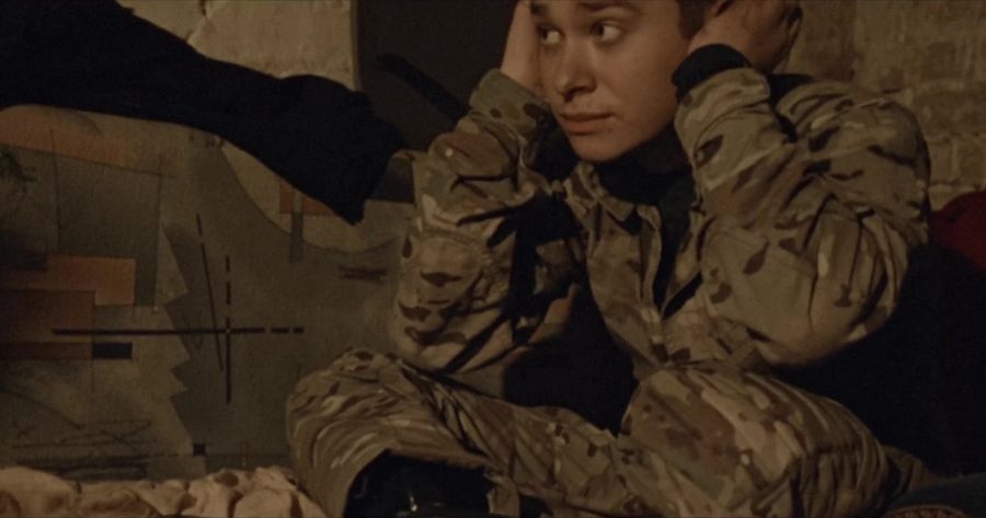A young soldier seated against a wall